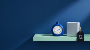 A round egg timer on a pale mint shelf against a deep cobalt wall, beside a small carton with a chalk tag reading 12 — a quick first stocktake of one shelf.