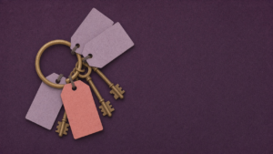 A ring of brass keys on a deep plum background, each key tied to a blank pale-lilac paper tag, with one soft coral tag at the front.