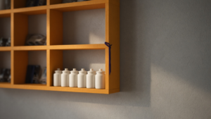 A row of saffron-orange wall cubbies on a slate-grey wall, with one lit cubby holding cream jars marked by an indigo thread.
